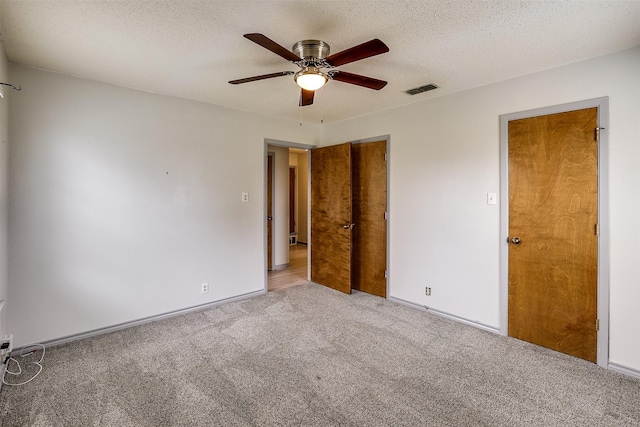 spare room featuring light carpet, ceiling fan, a textured ceiling, and visible vents