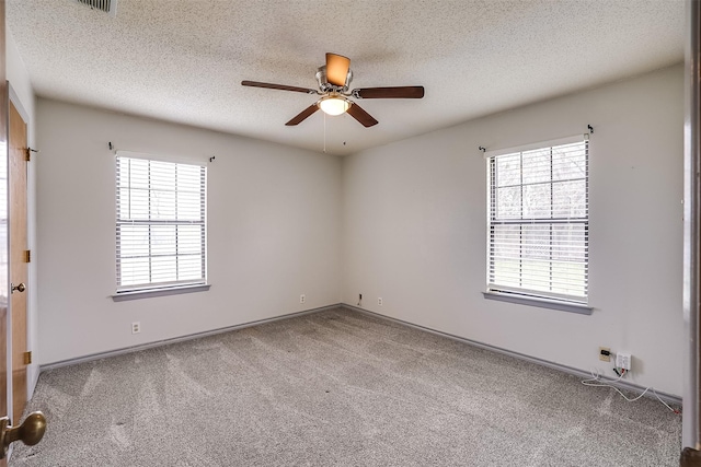 carpeted empty room featuring a textured ceiling, a wealth of natural light, and a ceiling fan