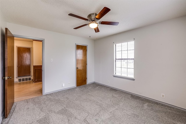 unfurnished bedroom featuring a textured ceiling, visible vents, baseboards, a ceiling fan, and carpet