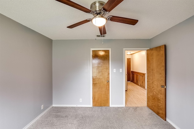 unfurnished bedroom with carpet, visible vents, ceiling fan, and a textured ceiling