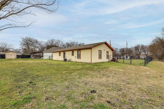 back of house with central AC unit, fence, and a yard