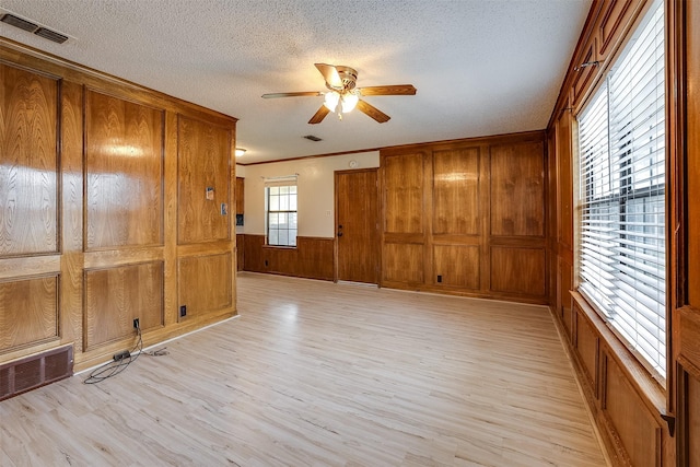 unfurnished room with light wood finished floors, visible vents, and a textured ceiling