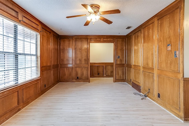 unfurnished room with a textured ceiling, light wood finished floors, and visible vents