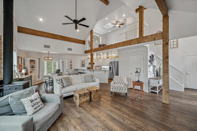 living area with visible vents, dark wood finished floors, beamed ceiling, a wood stove, and high vaulted ceiling