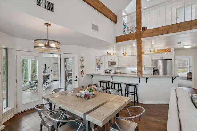 dining room featuring visible vents, dark wood-type flooring, and beam ceiling