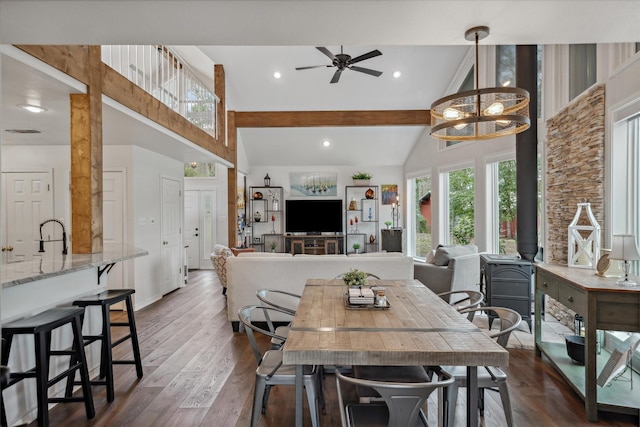 dining room featuring a wood stove, visible vents, high vaulted ceiling, and dark wood-style flooring