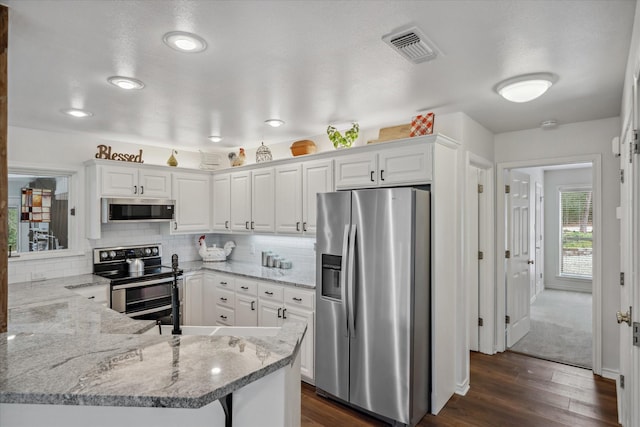 kitchen with white cabinets, visible vents, stainless steel appliances, and decorative backsplash