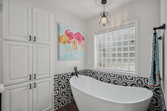 bathroom with a soaking tub and a notable chandelier