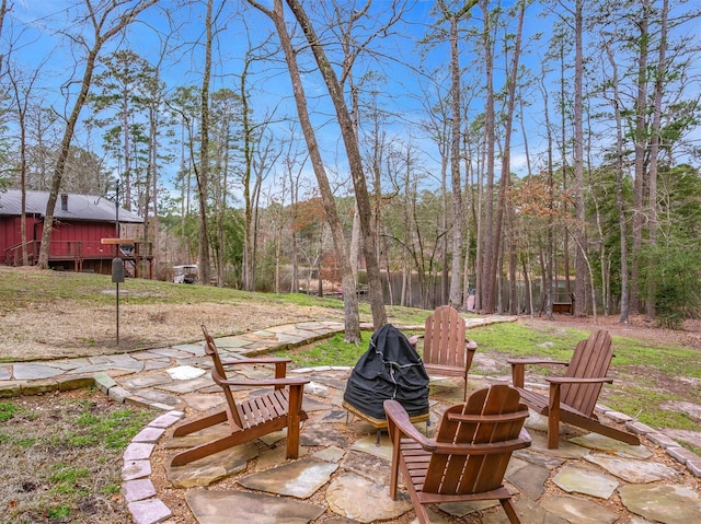 view of patio with a fire pit and a view of trees