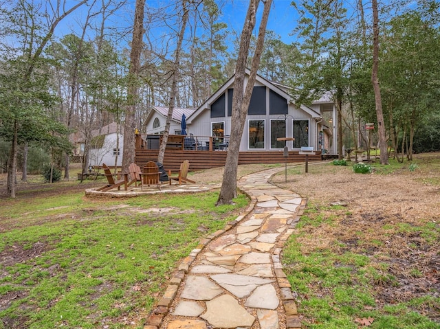 back of property with a deck and an outdoor fire pit