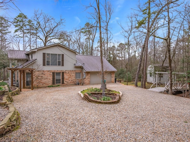 view of front facade with a garage, curved driveway, metal roof, and brick siding