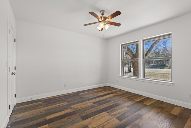 spare room featuring dark wood-type flooring, a ceiling fan, and baseboards