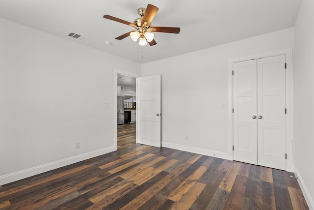 unfurnished bedroom with dark wood-type flooring, visible vents, ceiling fan, and baseboards