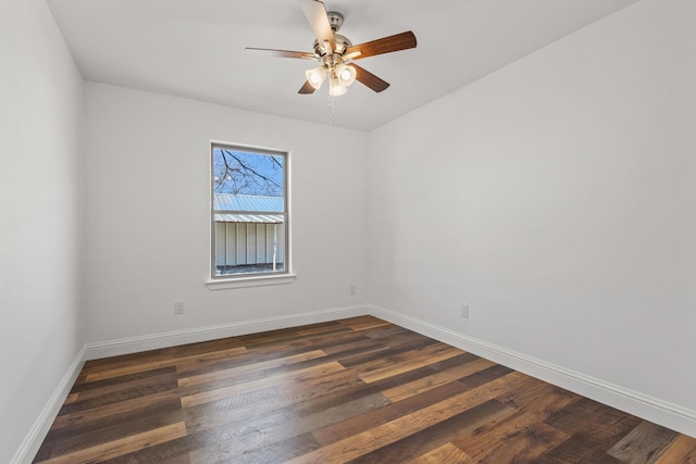 spare room with a ceiling fan, dark wood-style flooring, and baseboards