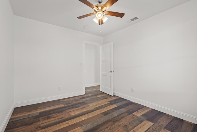 spare room with dark wood-style floors, visible vents, ceiling fan, and baseboards