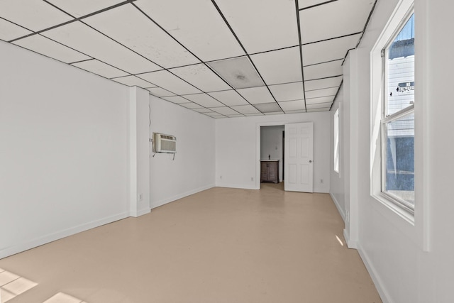 spare room with a drop ceiling, plenty of natural light, finished concrete flooring, and baseboards