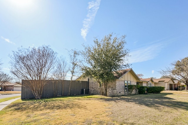 view of side of home featuring a yard, brick siding, and central AC unit