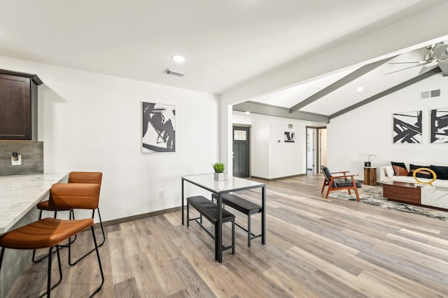 dining space featuring vaulted ceiling with beams, light wood finished floors, visible vents, and a ceiling fan