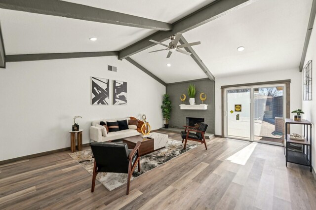 living area featuring visible vents, a fireplace, lofted ceiling with beams, and wood finished floors