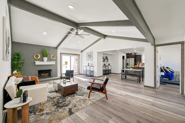 living room with light wood-style flooring, ceiling fan, vaulted ceiling with beams, a fireplace, and recessed lighting