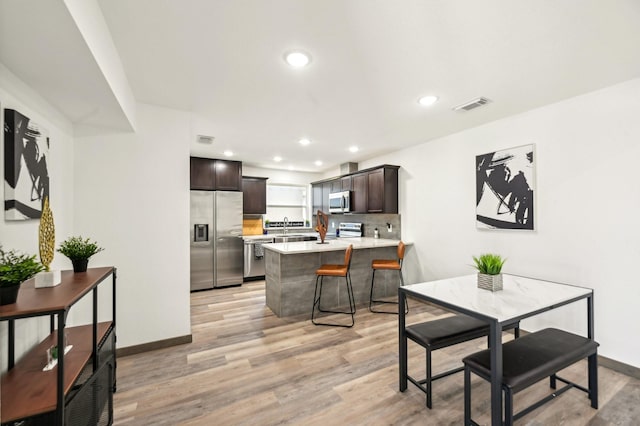 kitchen featuring light countertops, visible vents, appliances with stainless steel finishes, dark brown cabinetry, and a peninsula