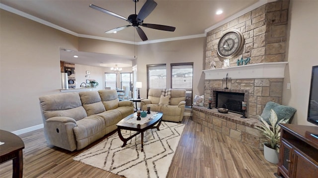 living area featuring ceiling fan with notable chandelier, wood finished floors, a fireplace, and ornamental molding