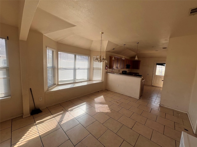 kitchen featuring lofted ceiling, a notable chandelier, a peninsula, visible vents, and pendant lighting