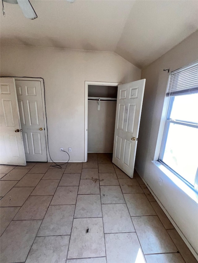 unfurnished bedroom featuring lofted ceiling, a ceiling fan, a closet, and light tile patterned flooring