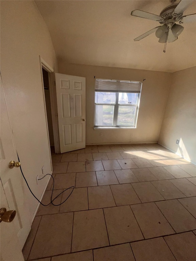 empty room with vaulted ceiling, light tile patterned floors, and a ceiling fan