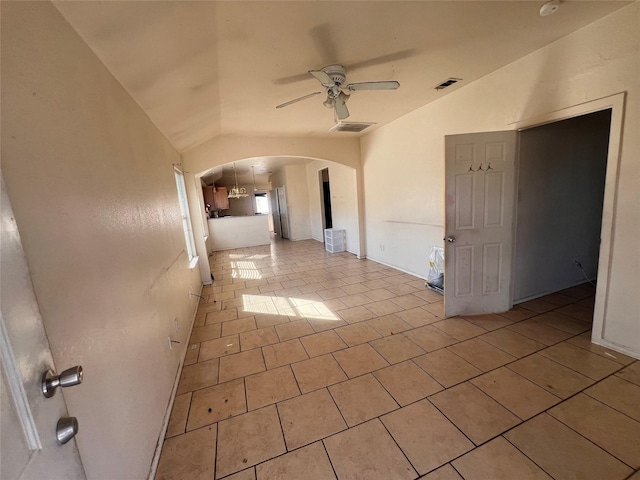 empty room with arched walkways, light tile patterned floors, lofted ceiling, visible vents, and a ceiling fan