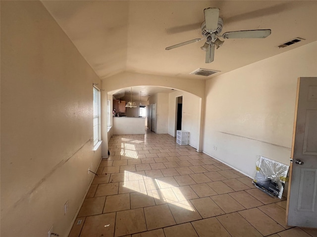 interior space with arched walkways, light tile patterned floors, visible vents, and a ceiling fan