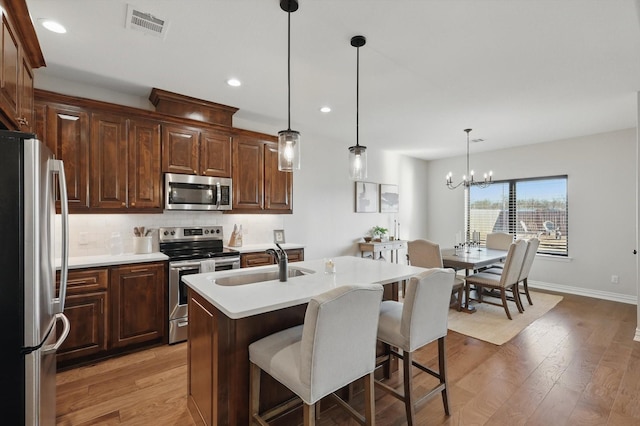 kitchen with light wood finished floors, visible vents, appliances with stainless steel finishes, and a sink