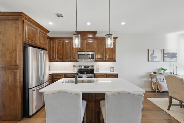 kitchen with visible vents, wood finished floors, stainless steel appliances, light countertops, and recessed lighting