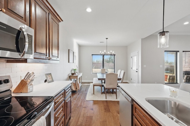 kitchen with decorative backsplash, appliances with stainless steel finishes, dark wood-type flooring, decorative light fixtures, and light countertops