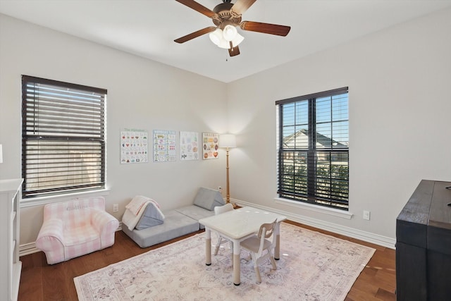 living area with ceiling fan, baseboards, and wood finished floors