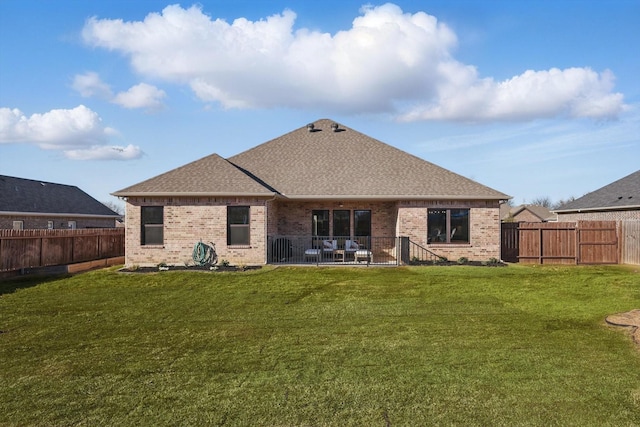 back of property featuring brick siding, a patio, roof with shingles, a lawn, and a fenced backyard