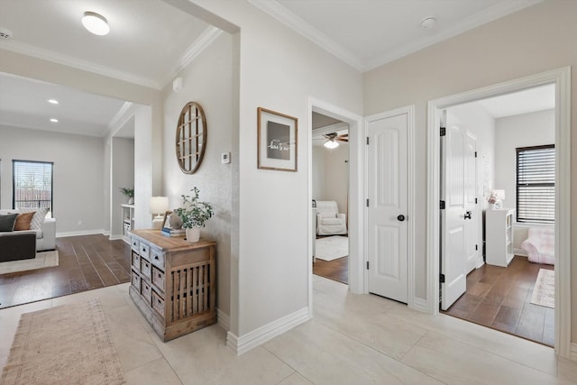 hallway with ornamental molding, a wealth of natural light, baseboards, and wood finished floors