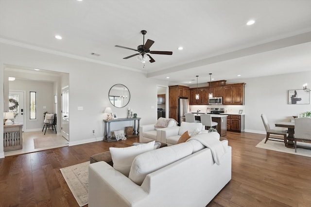 living area featuring baseboards, ornamental molding, wood finished floors, and recessed lighting