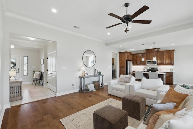 living room featuring light wood-style floors, baseboards, ornamental molding, and recessed lighting