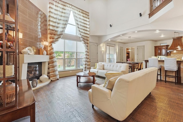 living area with arched walkways, a large fireplace, and a high ceiling