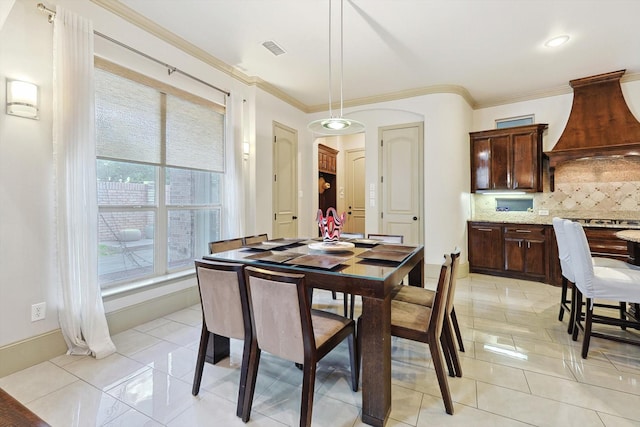 dining area featuring light tile patterned floors, baseboards, visible vents, and crown molding