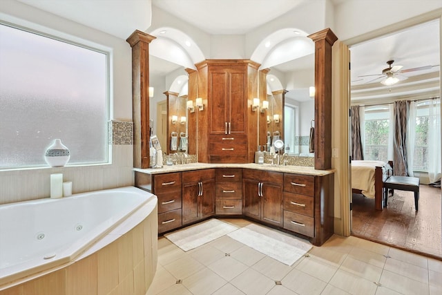 ensuite bathroom with ensuite bathroom, double vanity, a whirlpool tub, and decorative columns