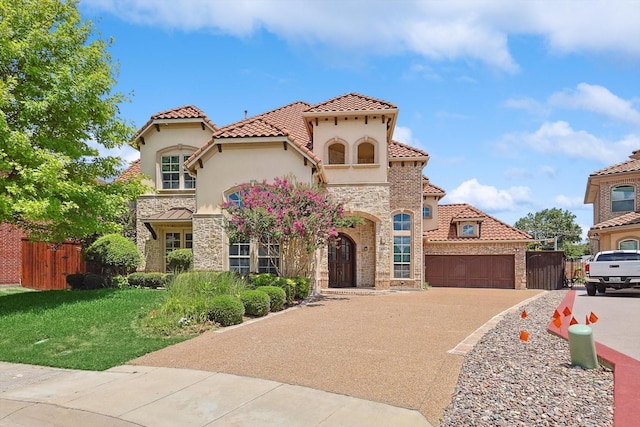 mediterranean / spanish-style house featuring driveway, a garage, stone siding, fence, and stucco siding