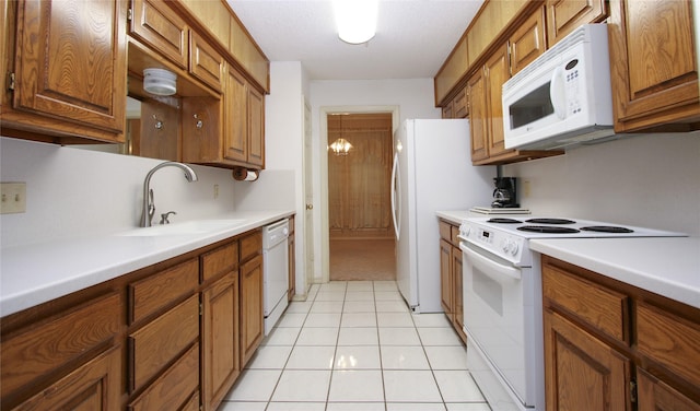 kitchen with white appliances, brown cabinets, a sink, and light countertops