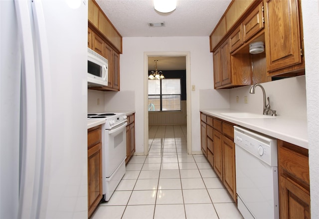 kitchen with light tile patterned floors, white appliances, a sink, visible vents, and light countertops