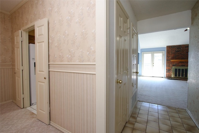 hallway with wallpapered walls, light tile patterned flooring, light colored carpet, and wainscoting