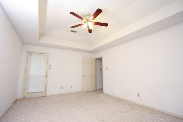 empty room featuring baseboards, visible vents, a raised ceiling, and a ceiling fan