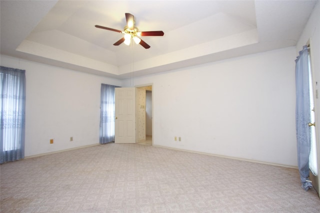 spare room featuring a raised ceiling and baseboards