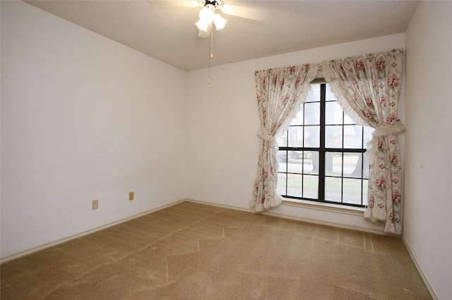 carpeted spare room with ceiling fan, a textured ceiling, and baseboards