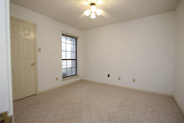 spare room featuring carpet floors, ceiling fan, and baseboards